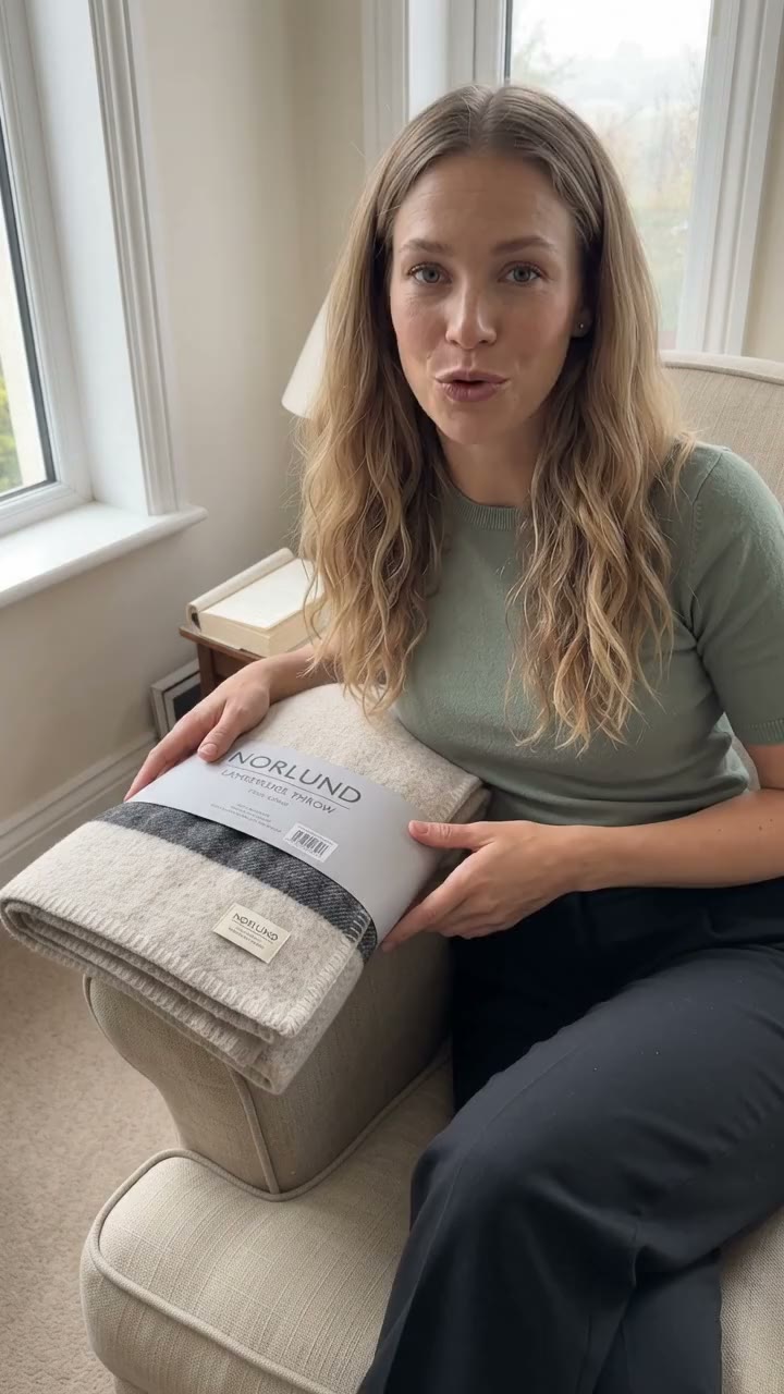 Vertical 9:16 ad: a woman on an armchair presents a NORLUND wool throw